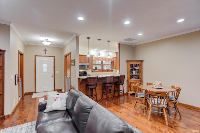 living room featuring sink, light wood-type flooring, and ornamental molding