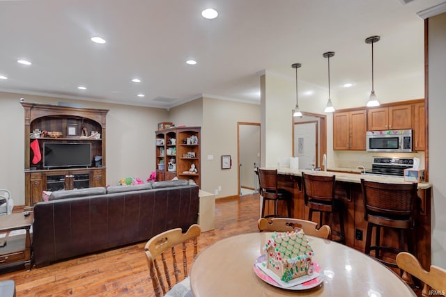 dining area featuring light hardwood / wood-style floors, crown molding, and sink