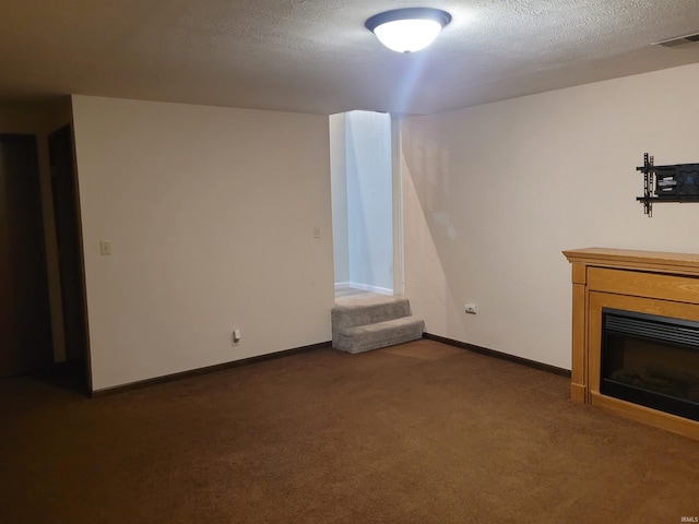 unfurnished living room featuring dark carpet and a textured ceiling