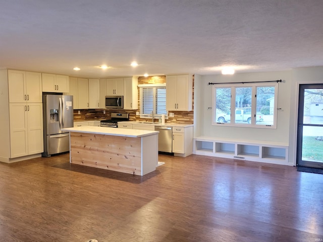 kitchen featuring a center island, sink, stainless steel appliances, backsplash, and hardwood / wood-style floors