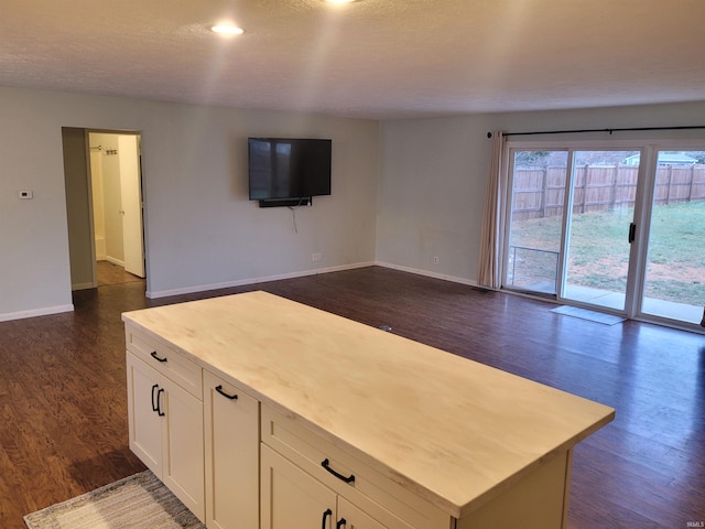 kitchen featuring white cabinets, dark hardwood / wood-style floors, a center island, and a textured ceiling