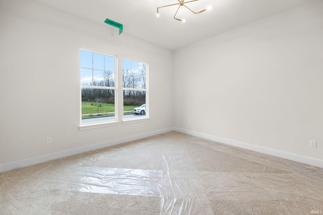 carpeted spare room featuring a chandelier