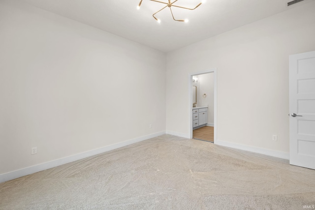 unfurnished bedroom featuring ensuite bathroom, light carpet, and an inviting chandelier