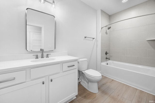 full bathroom featuring hardwood / wood-style flooring, vanity, toilet, and tiled shower / bath