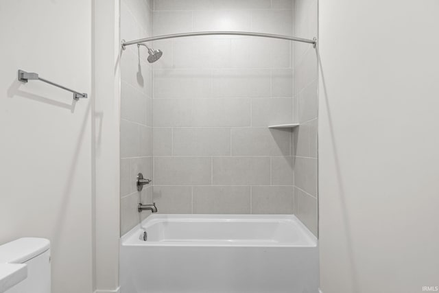 bathroom with toilet and tiled shower / bath