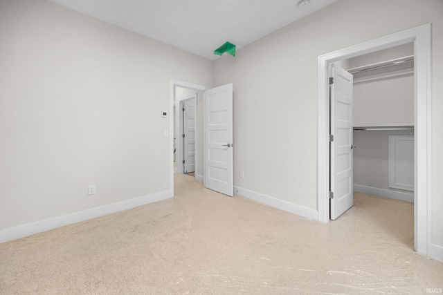 unfurnished bedroom featuring light carpet and a closet