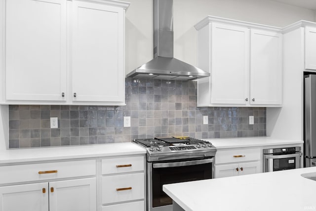 kitchen with white cabinets, appliances with stainless steel finishes, decorative backsplash, and wall chimney exhaust hood