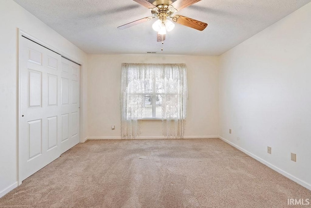 unfurnished bedroom with a textured ceiling, ceiling fan, light carpet, and a closet