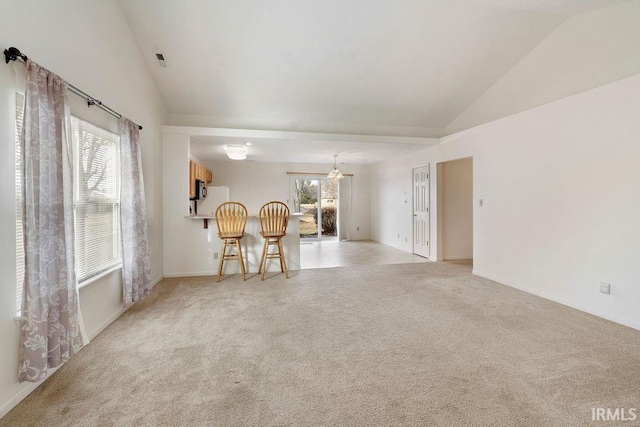 unfurnished living room featuring light carpet, a chandelier, and lofted ceiling