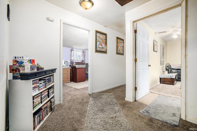 hall with light colored carpet and a textured ceiling