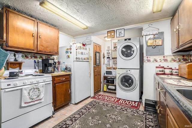 kitchen featuring a textured ceiling, white appliances, stacked washer / drying machine, and sink