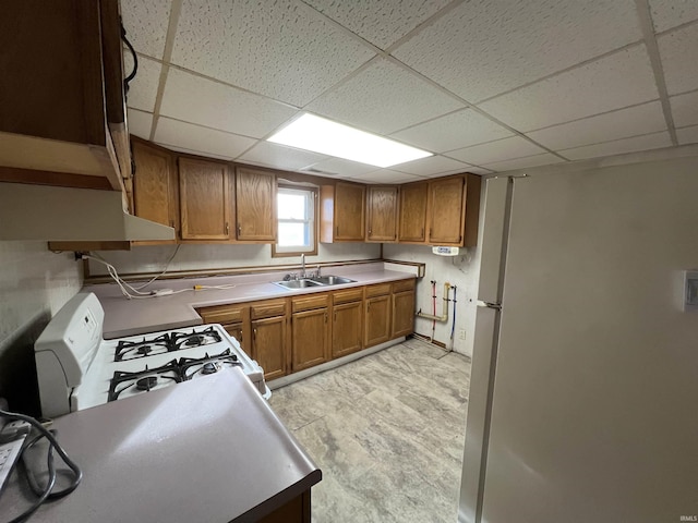 kitchen with white appliances, extractor fan, a paneled ceiling, and sink