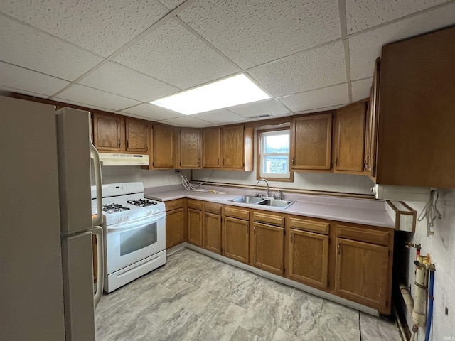 kitchen featuring a paneled ceiling, white appliances, and sink