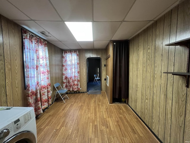 interior space with washer / clothes dryer, wood walls, and light hardwood / wood-style floors