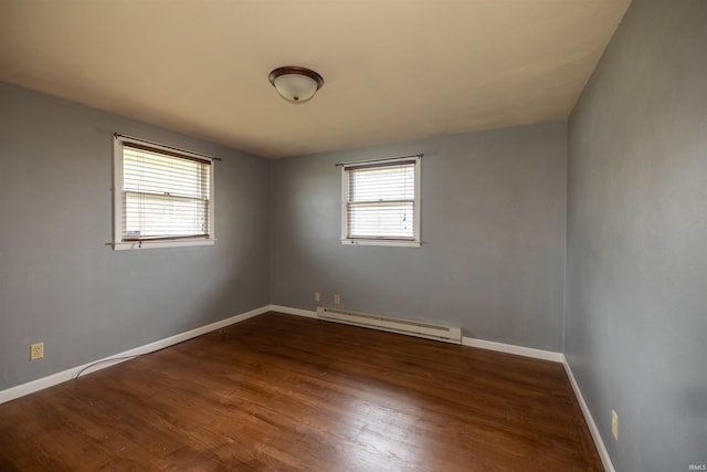 spare room with dark wood-type flooring and a baseboard heating unit