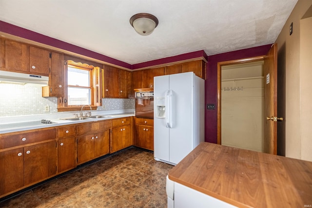 kitchen featuring tasteful backsplash, stainless steel oven, cooktop, sink, and white fridge with ice dispenser