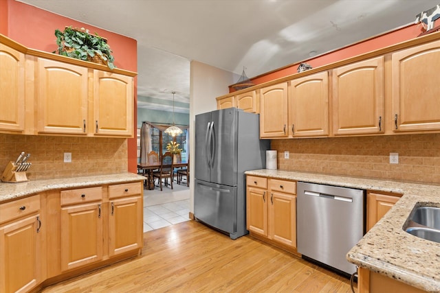 kitchen with light wood-type flooring, stainless steel appliances, an inviting chandelier, and tasteful backsplash