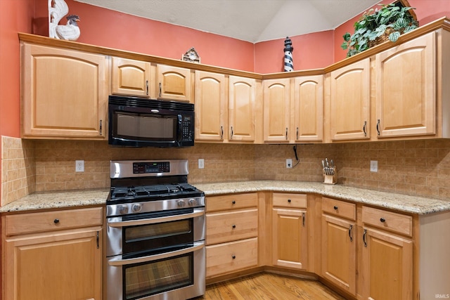 kitchen with backsplash, light stone counters, light hardwood / wood-style flooring, and stainless steel gas range