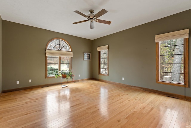 spare room with ceiling fan, light wood-type flooring, and a wealth of natural light