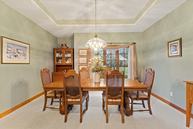 dining area featuring light carpet, a raised ceiling, and a notable chandelier