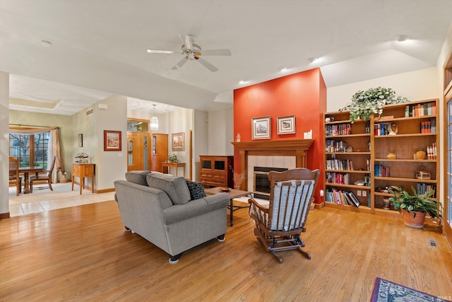 living room featuring ceiling fan, light hardwood / wood-style floors, and a fireplace