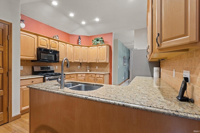 kitchen with light stone countertops, stainless steel range with gas cooktop, kitchen peninsula, and light hardwood / wood-style flooring