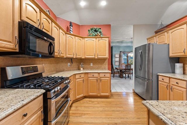 kitchen featuring light brown cabinets, light stone counters, light wood-type flooring, and appliances with stainless steel finishes