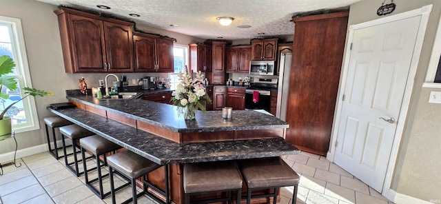 kitchen featuring a breakfast bar, appliances with stainless steel finishes, light tile patterned flooring, and sink