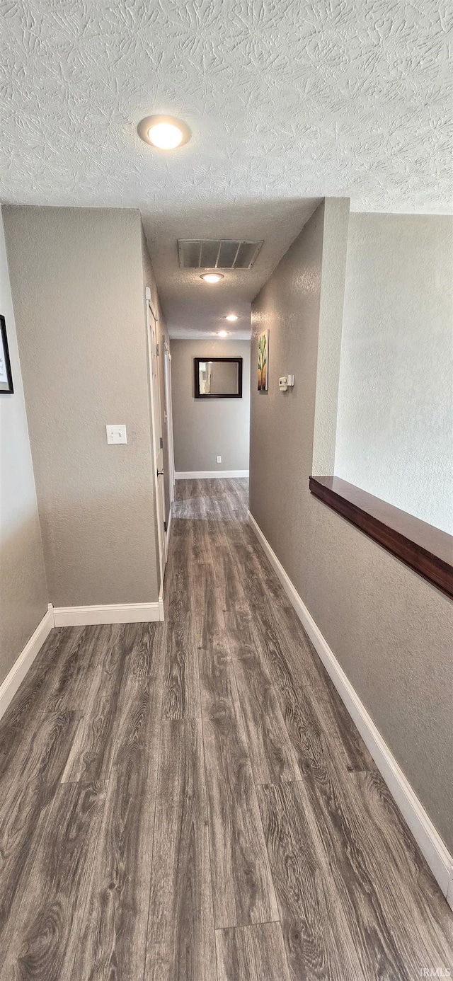 corridor featuring dark hardwood / wood-style flooring and a textured ceiling