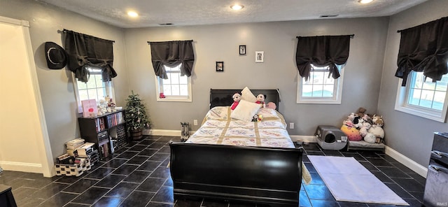 bedroom with a textured ceiling and multiple windows