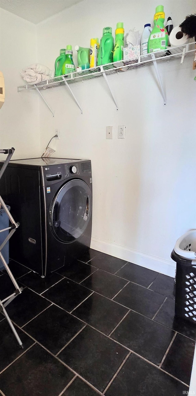 laundry room with dark tile patterned floors and washer / dryer