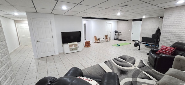 tiled living room with a drop ceiling and brick wall