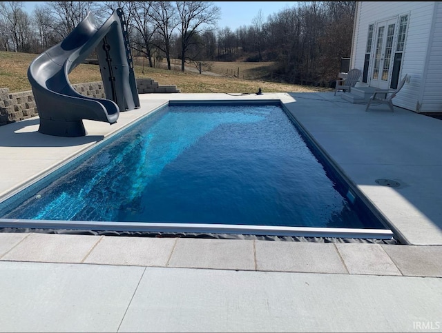 view of pool with a patio area, a water slide, and french doors