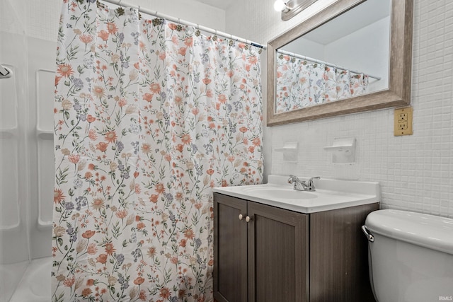 bathroom with vanity, toilet, and tile walls