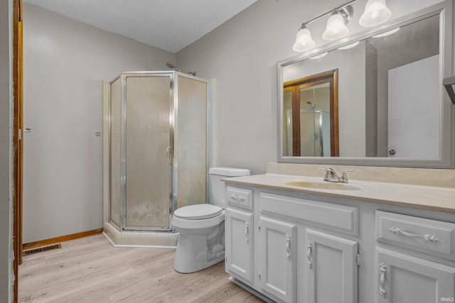 bathroom with hardwood / wood-style floors, vanity, toilet, and a shower with door