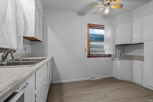 kitchen featuring light wood-type flooring, white cabinetry, ceiling fan, and sink