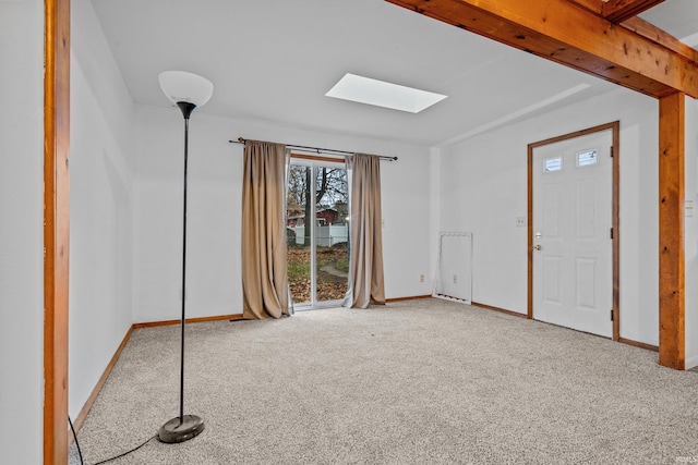 carpeted entryway with beam ceiling and a skylight