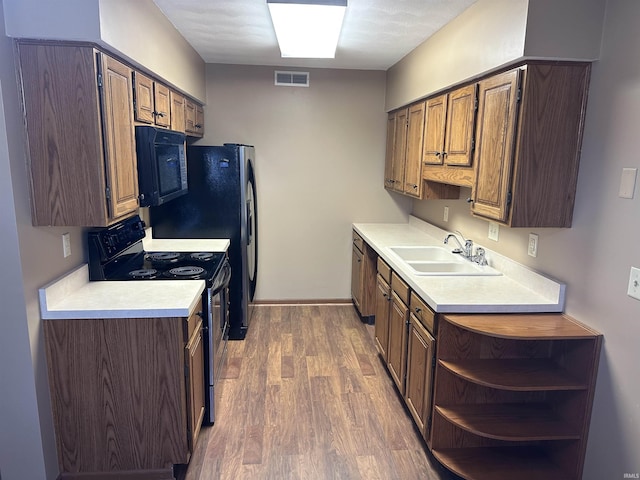 kitchen with black appliances, dark hardwood / wood-style flooring, and sink