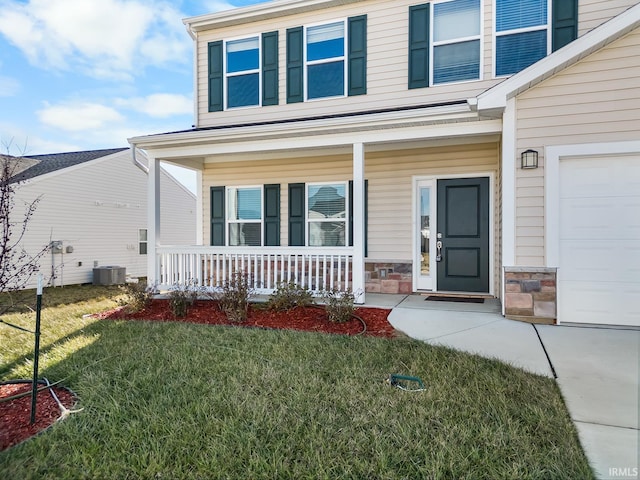 view of exterior entry featuring a porch, a yard, a garage, and central air condition unit