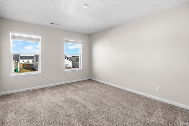 carpeted empty room with a textured ceiling