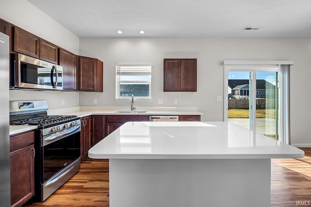 kitchen featuring hardwood / wood-style flooring, a center island, sink, and appliances with stainless steel finishes