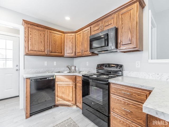 kitchen with sink, black appliances, and light hardwood / wood-style flooring