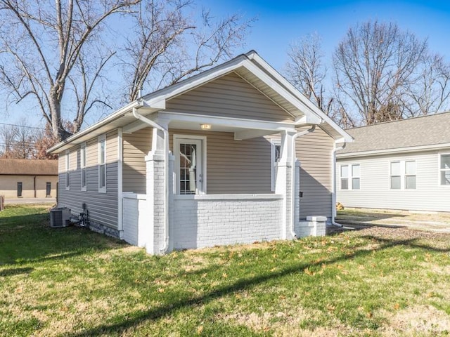 bungalow-style house featuring a front lawn and cooling unit