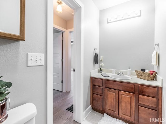 bathroom with wood-type flooring, vanity, and toilet