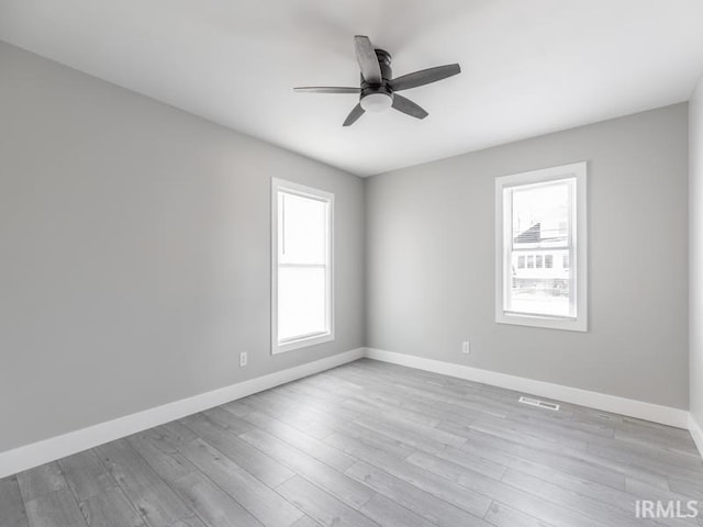 spare room with ceiling fan, a healthy amount of sunlight, and light wood-type flooring