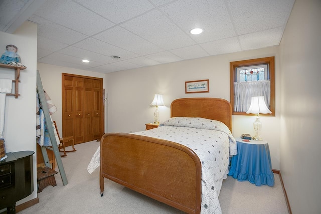 carpeted bedroom with a paneled ceiling and a closet