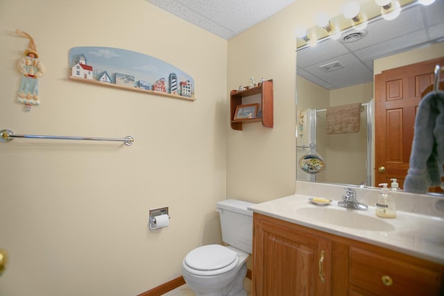 bathroom with vanity, toilet, walk in shower, and a drop ceiling