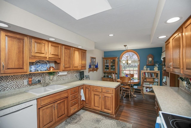 kitchen featuring sink, hanging light fixtures, dark wood-type flooring, kitchen peninsula, and white appliances