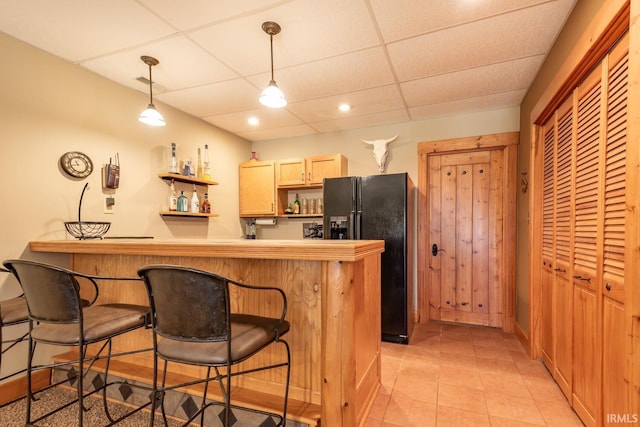 kitchen featuring kitchen peninsula, a drop ceiling, black refrigerator with ice dispenser, and hanging light fixtures