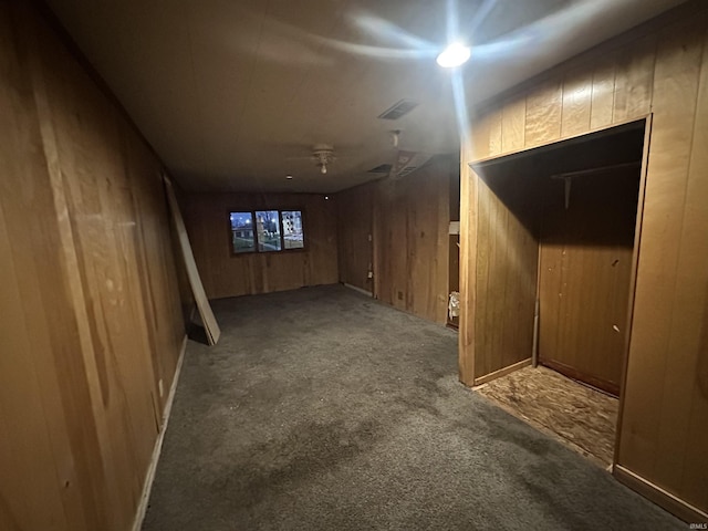 basement featuring carpet flooring and wood walls